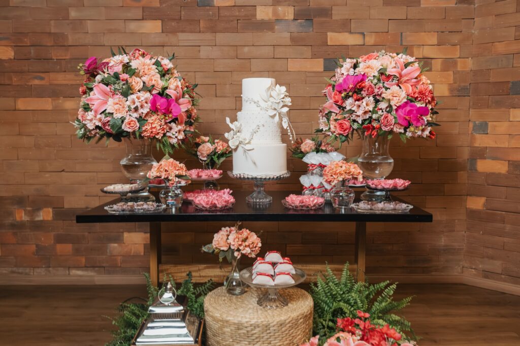 Luxurious wedding cake display with lush floral arrangements in a rustic setting.