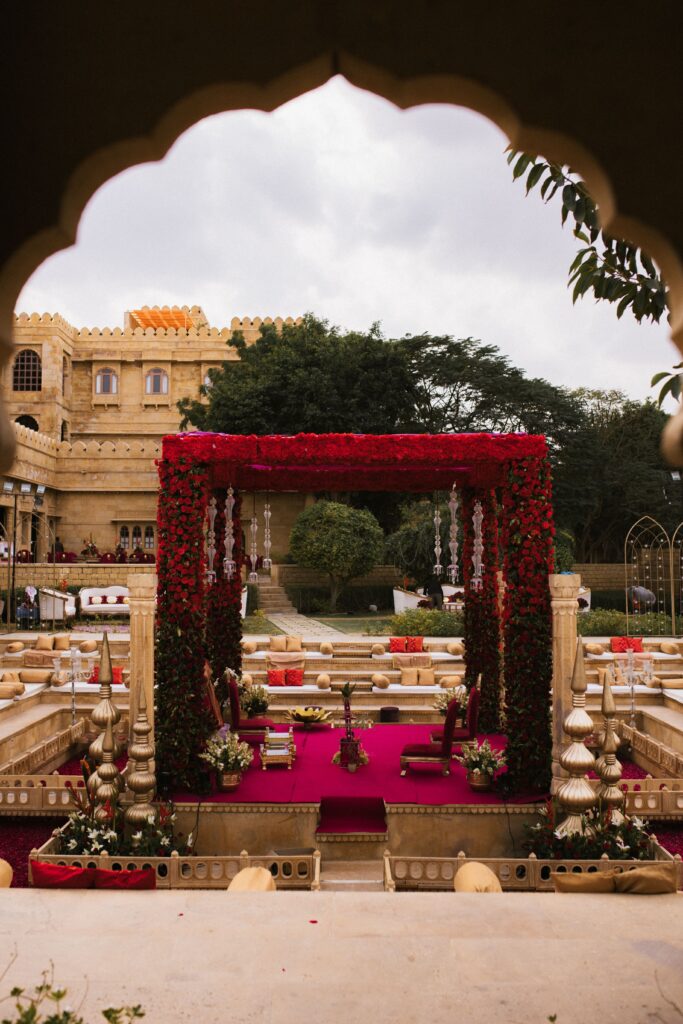 Ornate mandap setup in outdoor historic fort for an Indian wedding ceremony.
